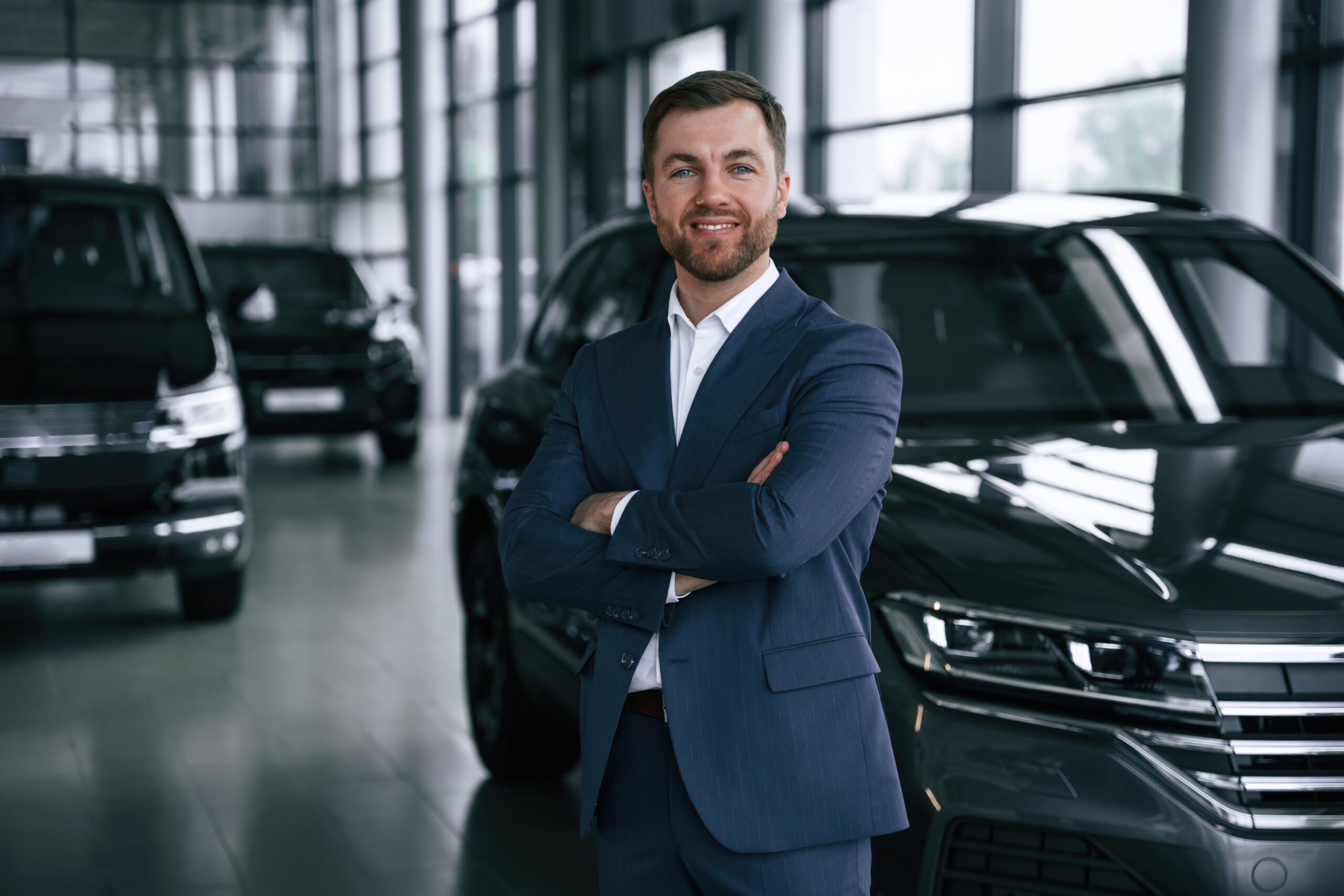 Cheerful salesman. Guy is in a car dealership.